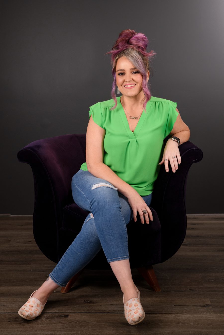Jen Rodgers seated and smiling in a green top and jeans